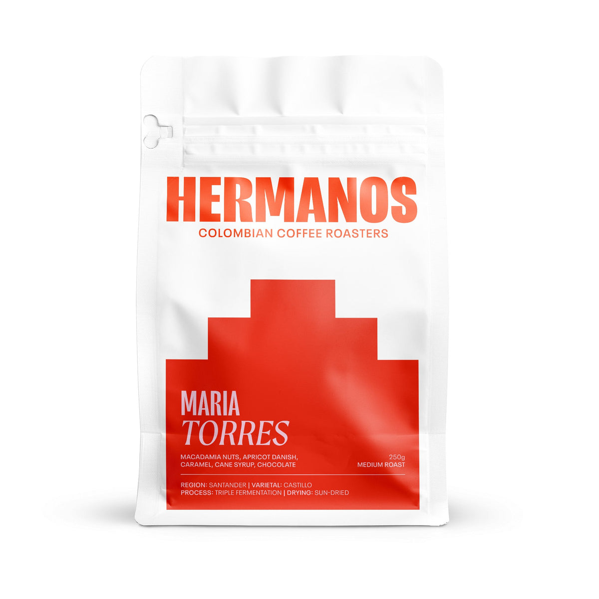 Front view of a white pouch of Hermanos Maria Torres Colombian specialty coffee, featuring a bold red geometric design and product details.