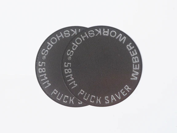 Close-up view of a two-pack of Weber Workshops 58mm stainless steel espresso puck saver screens on a plain white background.
