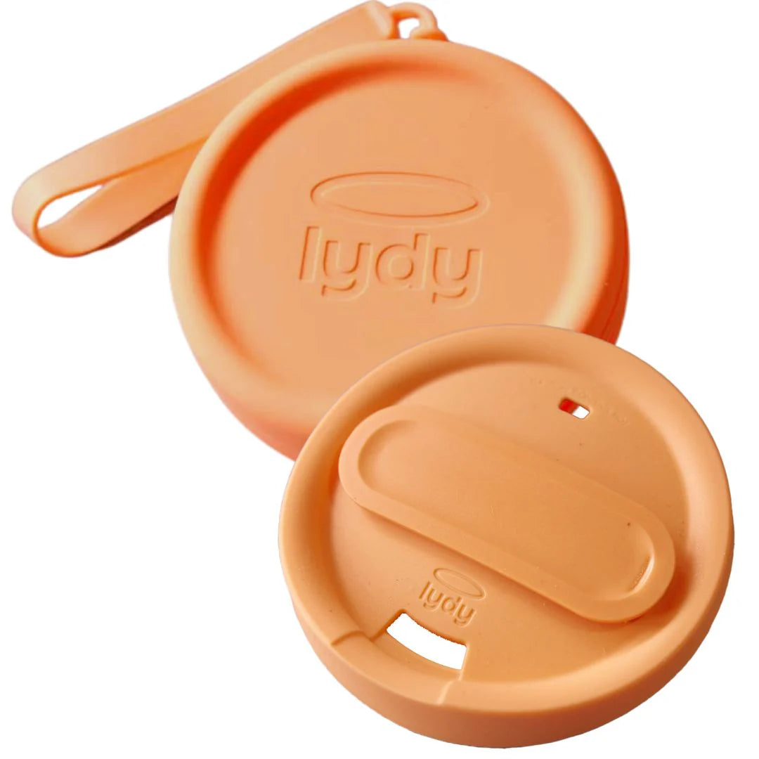 Angled close-up of a peach-colored Lydy reusable silicone coffee cup lid and its matching carrying strap.